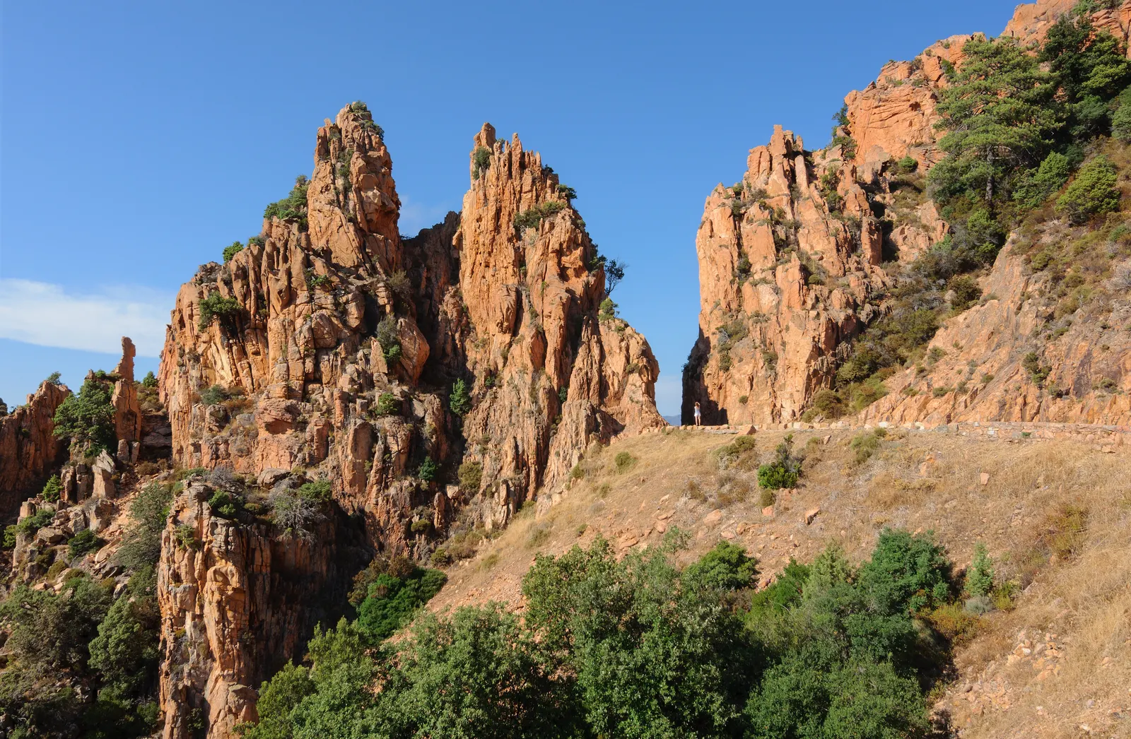 Aiguilles de granit rouge des calanques de Piana au bord de la route, sous un ciel bleu