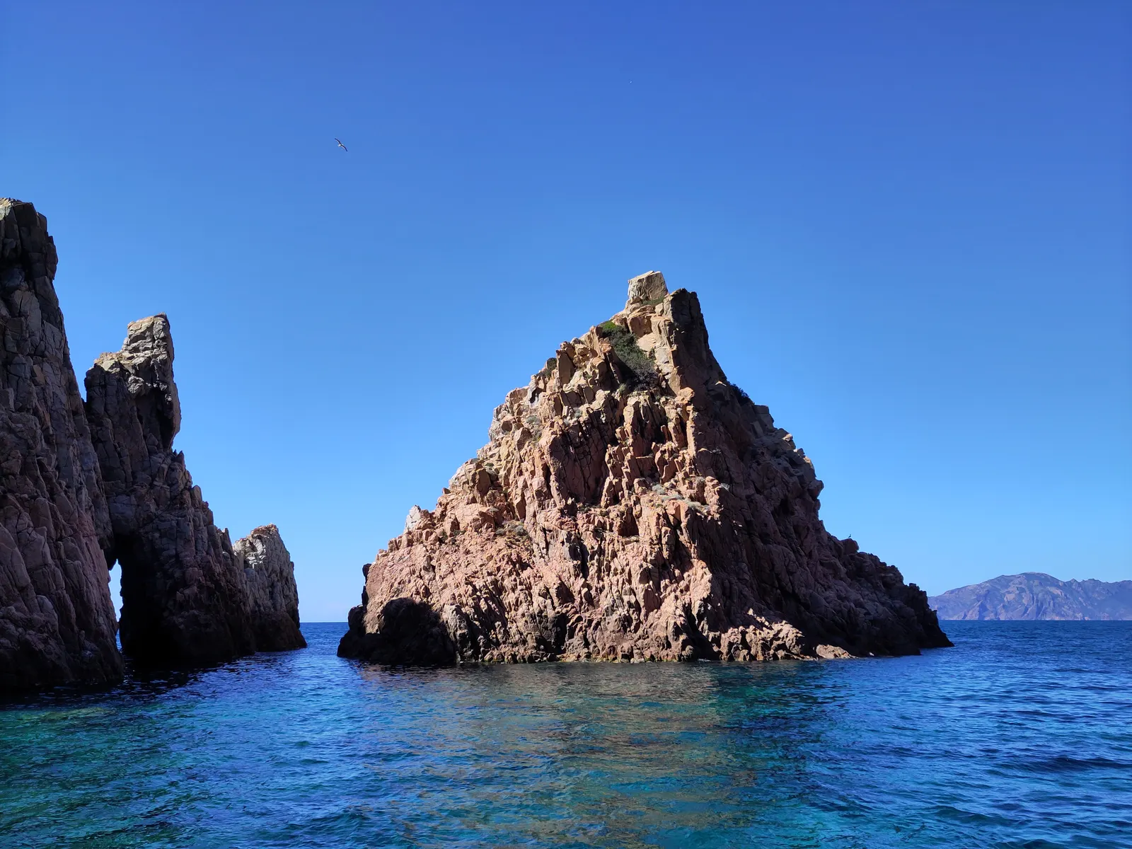 Rochers et arche de roche rouge dans la mer bleue de la réserve naturelle de Scandola
